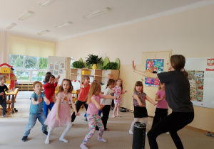 Grupa naśladuje ruchy taneczne instruktora