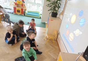 Dzieci oglądają ilustracje Układu Słonecznego na tablicy interaktywnej.