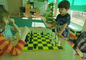 Czworo dzieci zgromadzonych wokół szachownicy.
