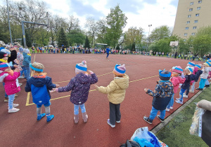 Dzieci stoją w kole na boisku.