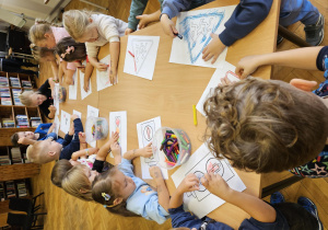 Dzieci kolorujące katrki w bibliotece