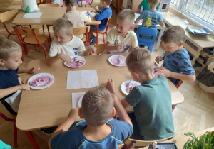 Dzieci jedż przy stolikach lody owocowe
