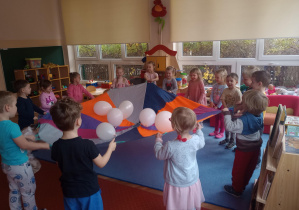 Dzieci korzystając z chusty animacyjnej bawią się balonami