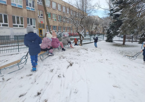 Dzieci jadą na sankach tworząc kulig