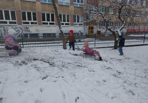 Dzieci zjeżdżają na sankach z górki