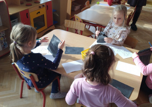 Dzieci siedzą przy stolikach i kalkują rysunki
