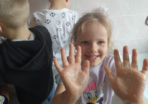 Dziewczynka pokazuje namydlone ręce