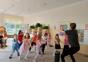 Grupa naśladuje ruchy taneczne instruktora