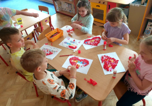 Dzieci wyklejają serca kulkami z bibuły
