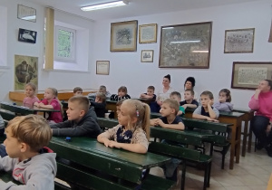 Grupa siedzi w starodawnych ławkach