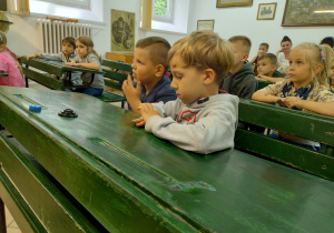 Dzieci w zabytkowych ławkach szkolnych