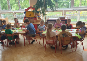 Dwa stoliki dzieci wycinają elementy z papieru kolorowego