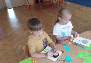 Chłopiec i dziewczynka wyklejają laurki