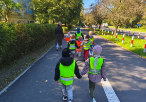 Grupa dzieci idzie w parach przez park
