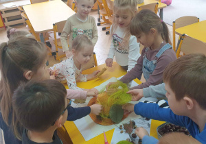 Dzieci wyklejają kapelusz liśćmi