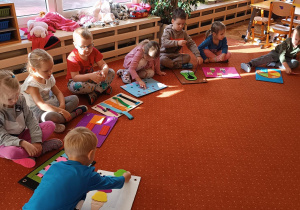 Dzieci siedzą na dywanie