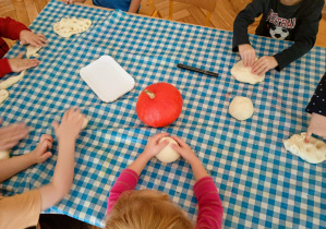 Dzieci przy stoliku lepią dynie z masy solnej