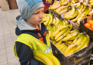 Chłopiec stoi przy stoisku z bananami