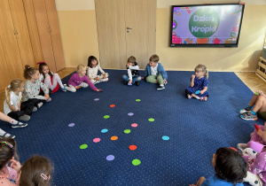 Dzieci siedzą w kole na dywanie