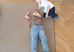 Chłopcy układają kolegę w pozycji bezpiecznej