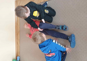 Chłopcy układają kolegę w pozycji bezpiecznej