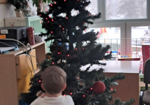 Chłopiec zawiesza na choince ozdobę choinkową