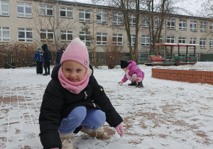 Dziewczynka w ogrodzie przedszkolnym w czasie pierwszego śniegu