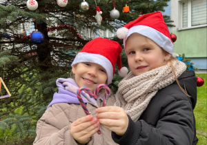 Dziewczynkimstoja przed ubraną choinką