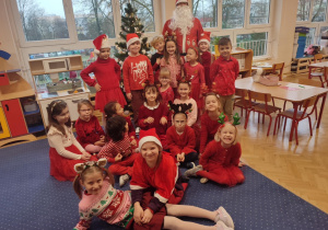 Dzieci ubrane na czerwono pozują do zdjęcia z Mikołajem