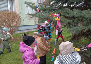 Dzieci wieszają kolorowy łańcuch na choince