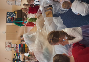 Dzieci tzymają wspólnie jedną dużą białą folię.