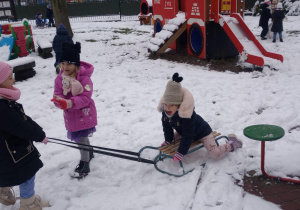 Dzieci ciągną się na sankach