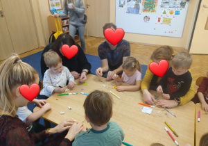 Rodzice z dziećmi siedzą przy stole warsztatowym