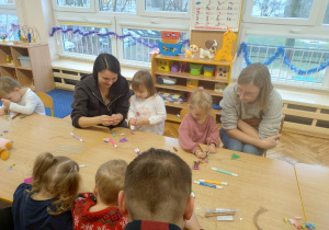 Dziewczynki z mamami dekorują sylwety choinek