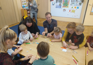 Dzieci oklejają choinki koralikami