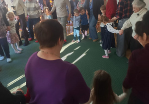 Dziadkowie tańczą w kole z wnuczkami
