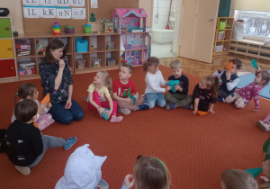 Dzieci słuchają co opowiada Pani