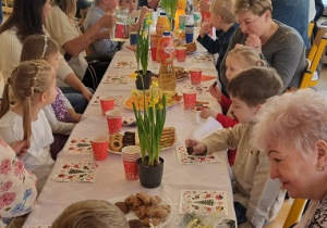 Babcie i dziadkowie siedzą przy stole z wnukami