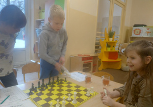 Dzieci patrzą na szachownicę.
