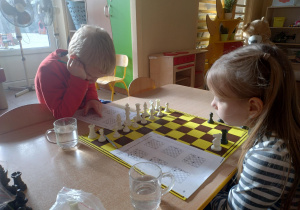 Dzieci patrzą na szachownicę.