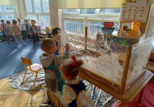 Grupa maluje na foli białą farbą