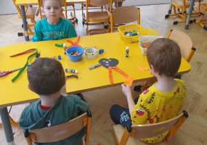 Chłopcy wykonują serduszka z papieru kolorowego