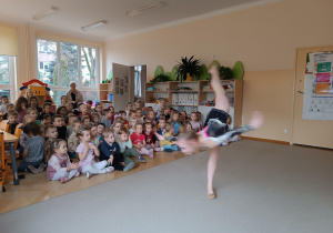 Dziewczynka pochyla się, unosząc jednocześnie prostą nogę.