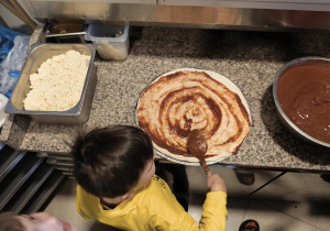 Chłopiec smaruje ciasto sosem