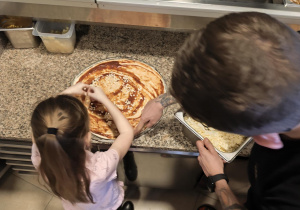 Dziewczynka posypuje ciasto serem