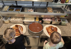 Dziewczynka i chłopiec smarują ciasto sosem