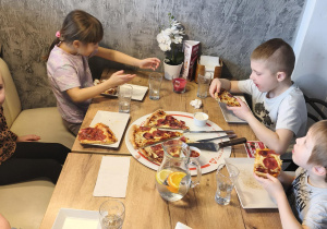 Dzieci jedzą pizzę