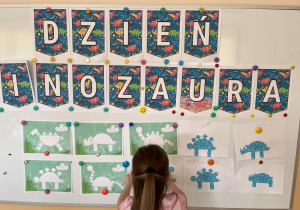 Dziewczynka przyczepia pracę na tablicę