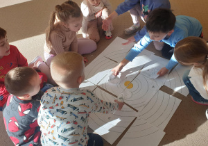 Dzieci na dywanie układają planety