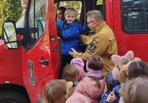 Chłopiec siedzi za kierownicą wozu strażackiego